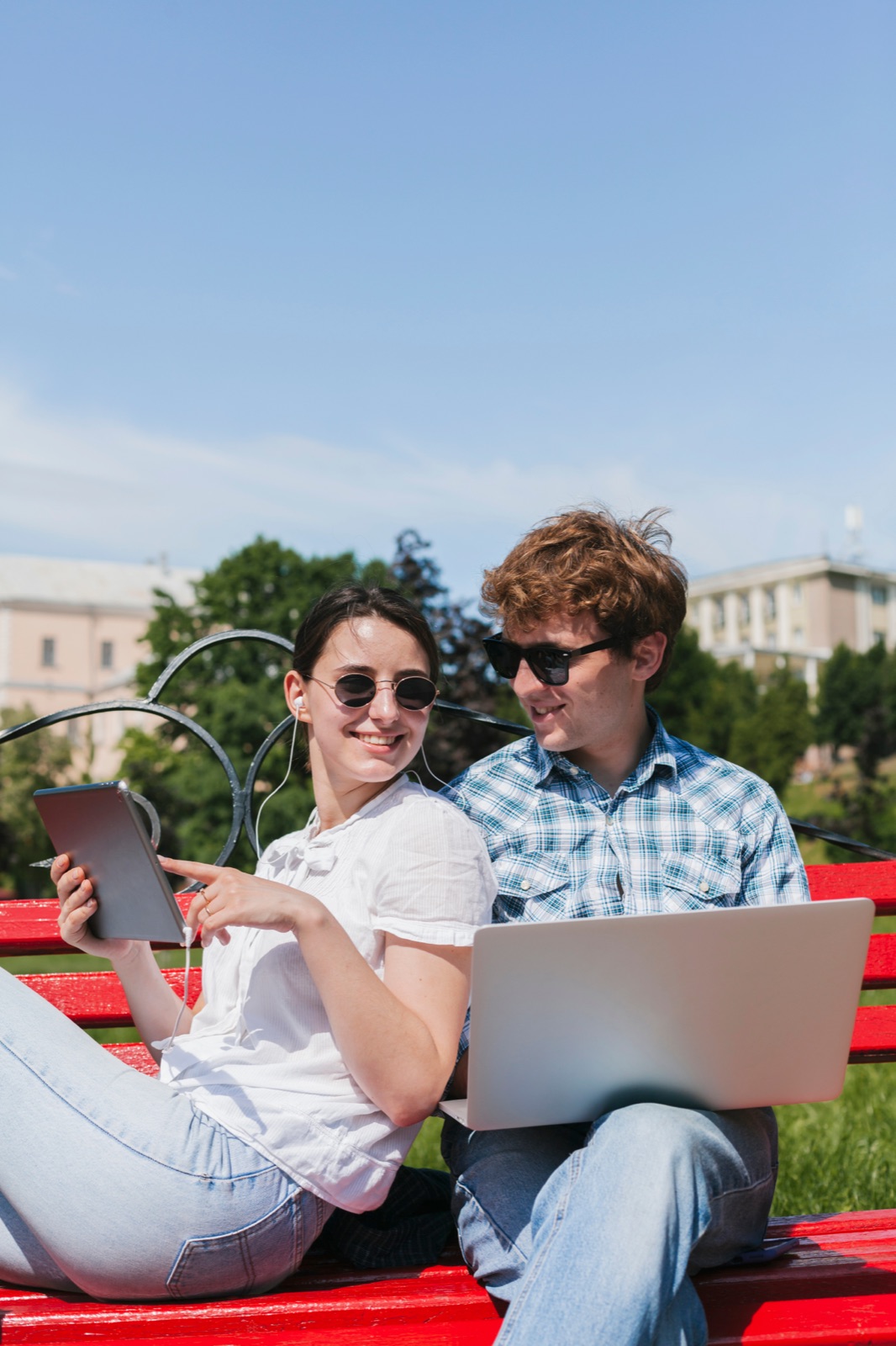 Pareja joven con tablet y laptop en un parque