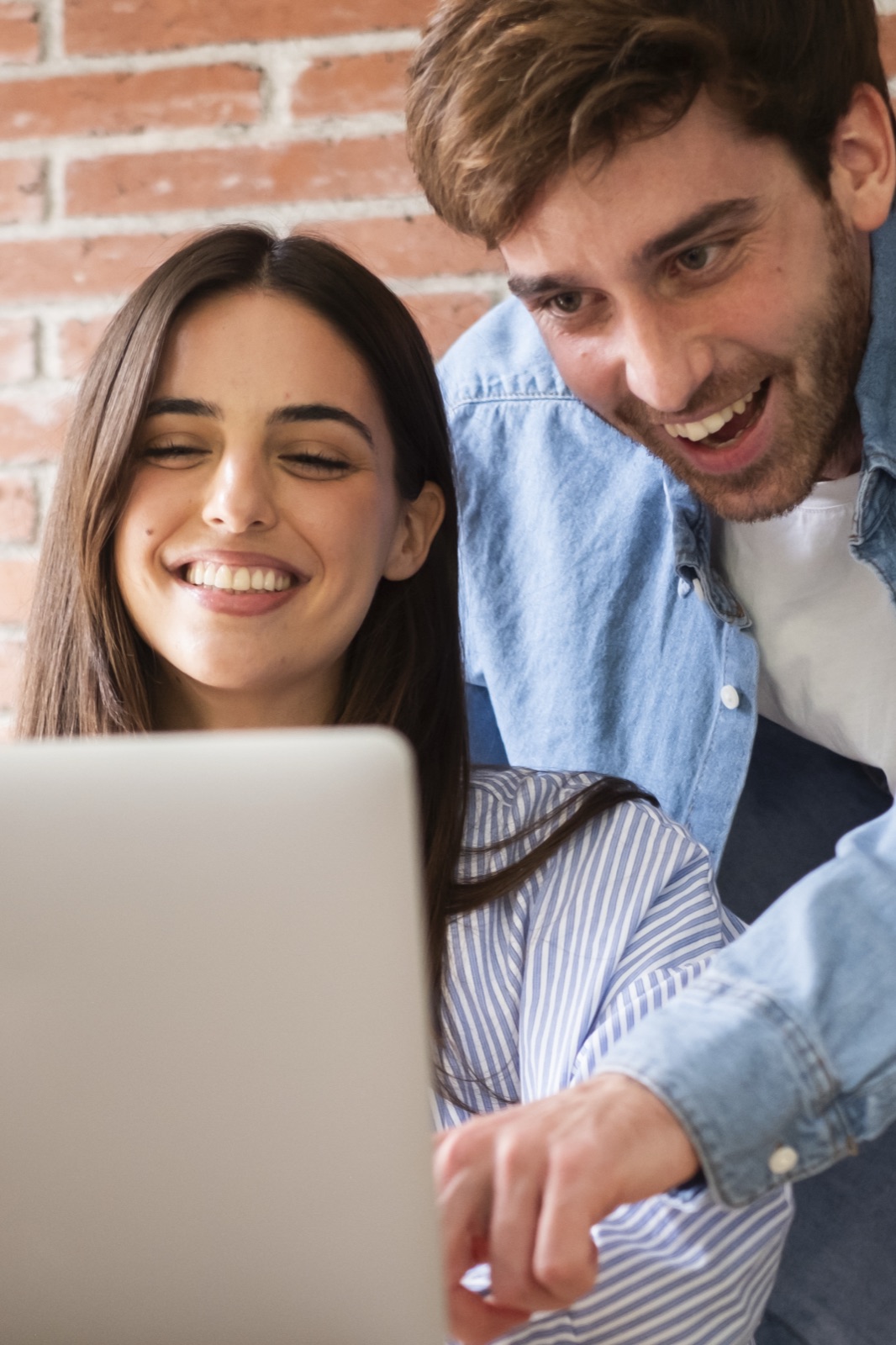 Pareja joven sonriendo frente a un computador